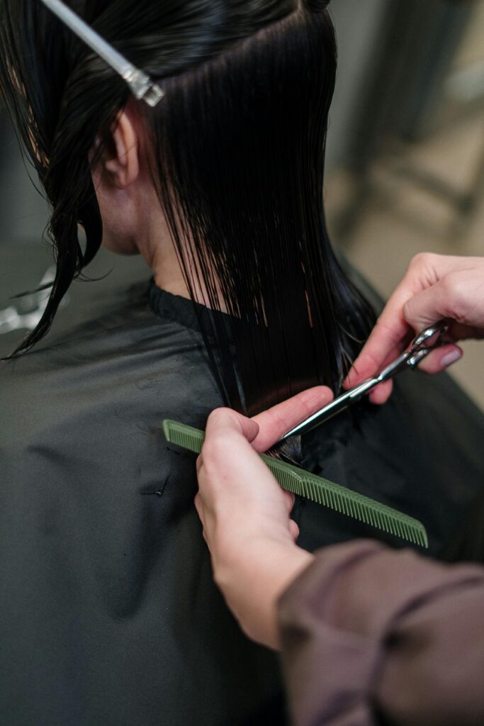 Close-up of a hairstylist cutting a woman's hair in a salon, showcasing precise techniques.